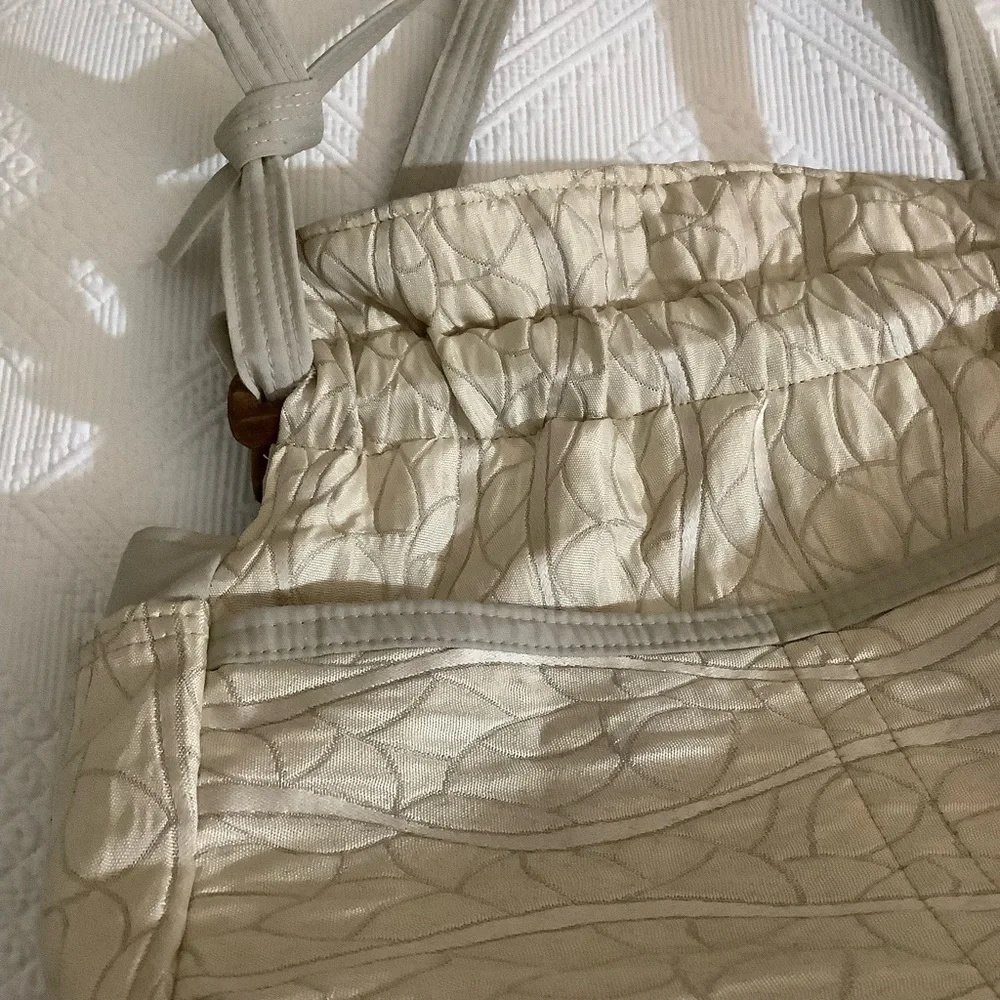 FABRIC SHOULDER BAG WITH OUTSIDE SURROUNDING POCKETS IN A CREAM AND TAUPE COLOR.